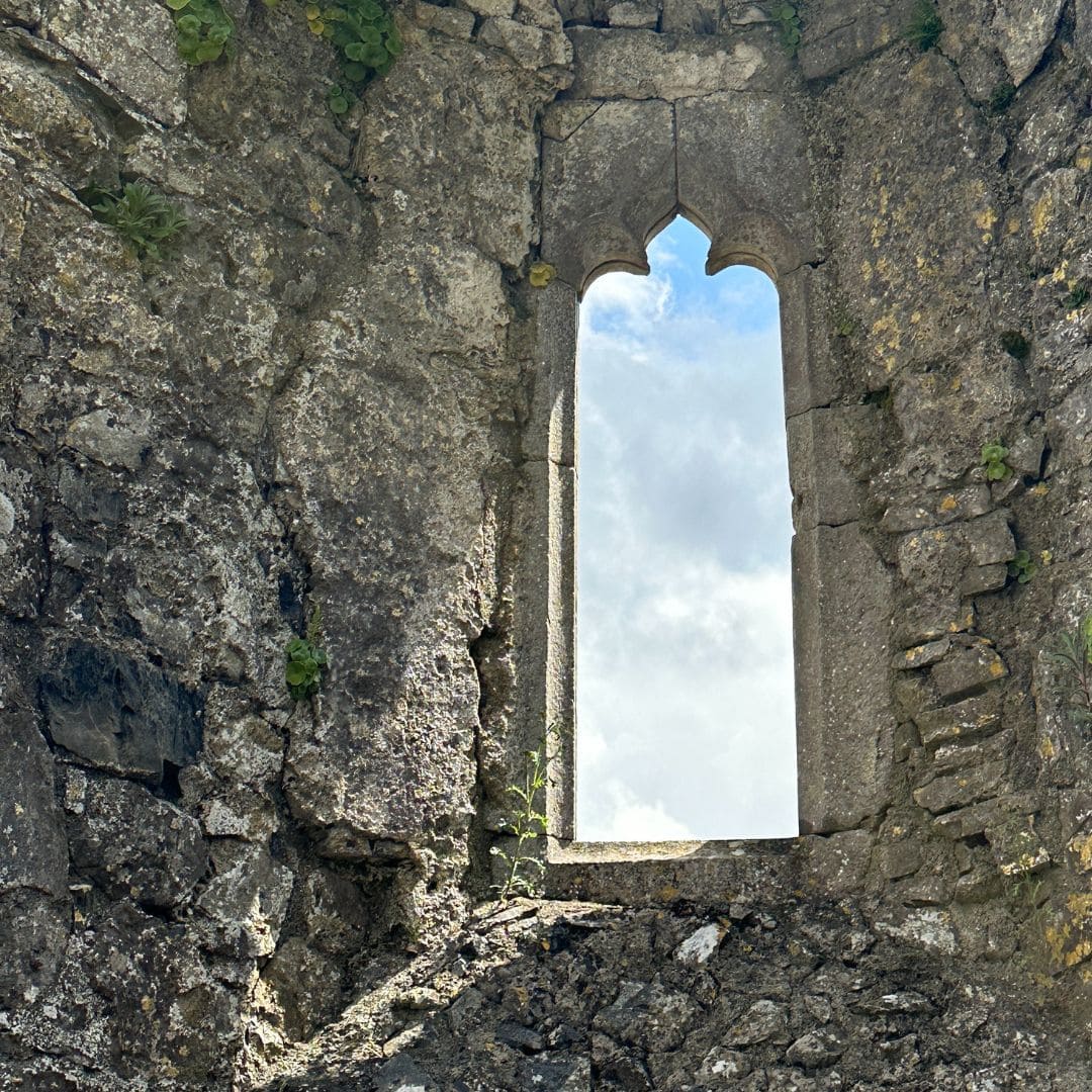 looking out a chapel window to the blue sky and sunlight shining through