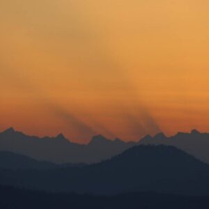 first rays of sunlight peeking over the misty dark mountains