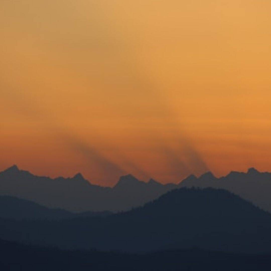 first rays of sunlight peeking over the misty dark mountains