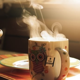 steaming mug of coffee with an owl design
