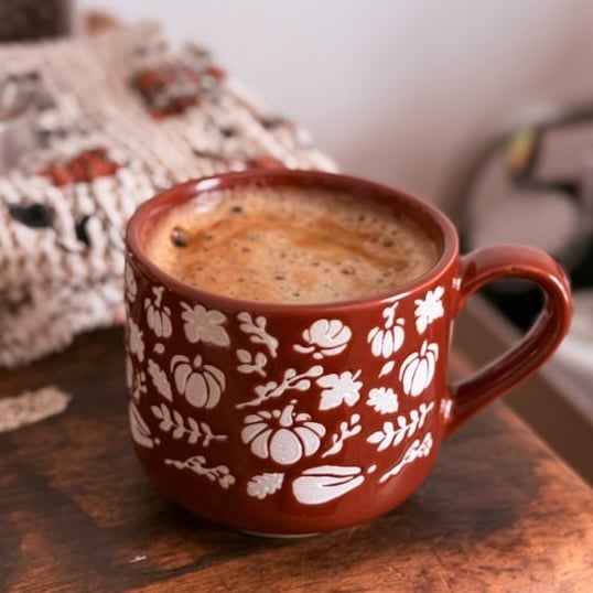 orange colored coffee mug with pumpkins and squash decorating it