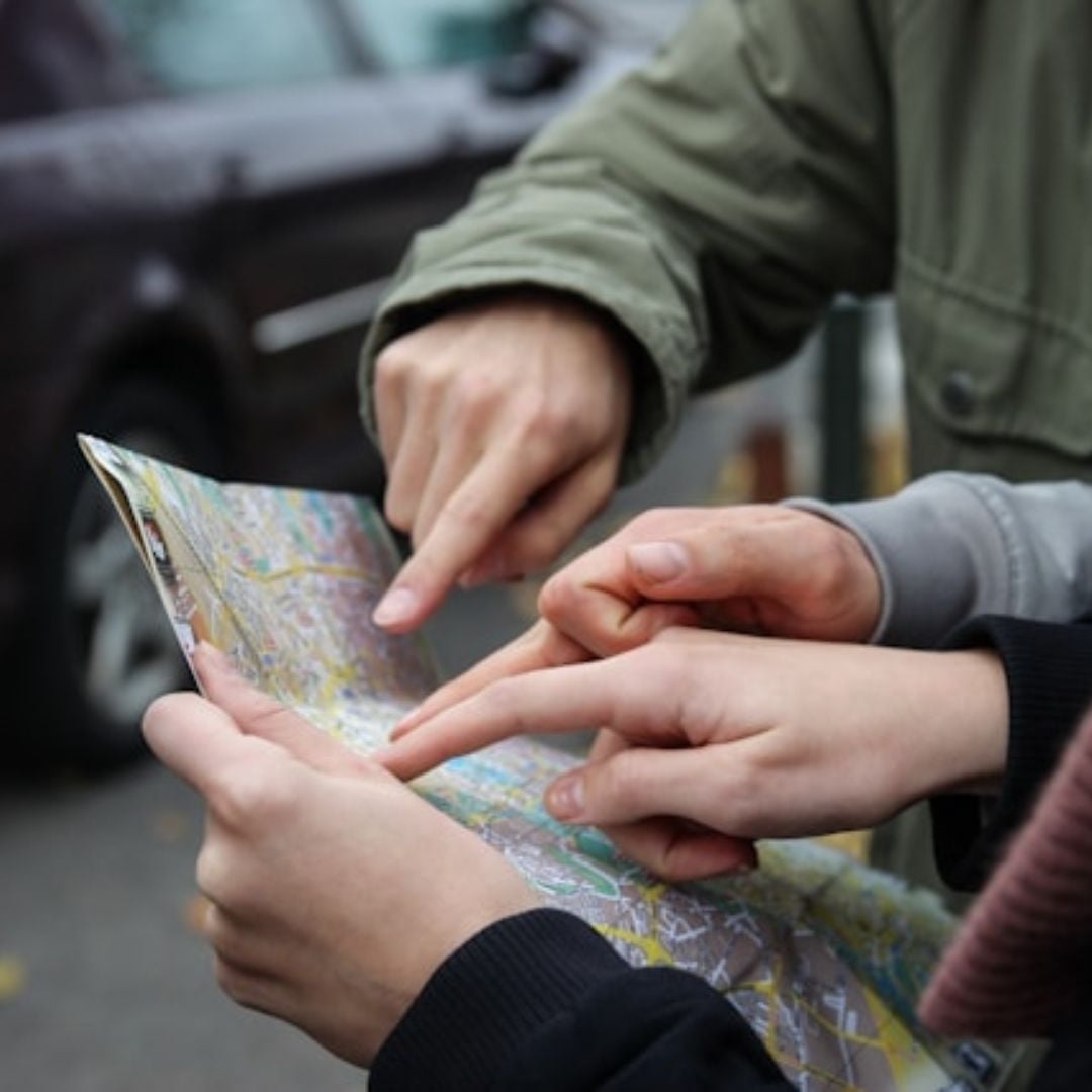 close-up of map with 3 people pointing at the same spot