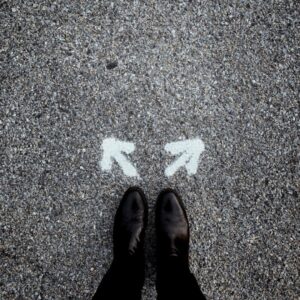 boots on pavement with 2 white arrows pointing in different directions
