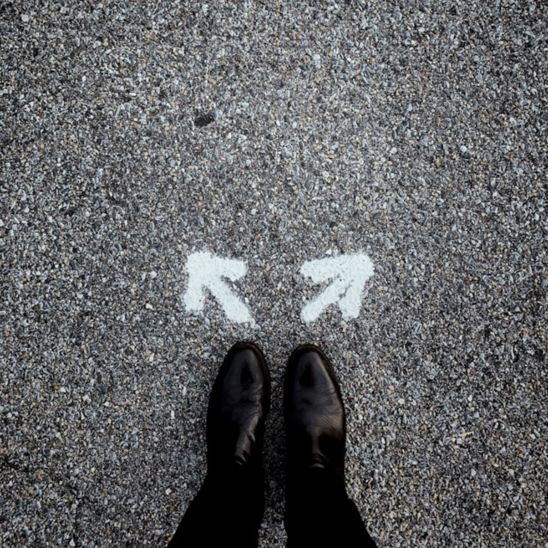 boots on pavement with 2 white arrows pointing in different directions