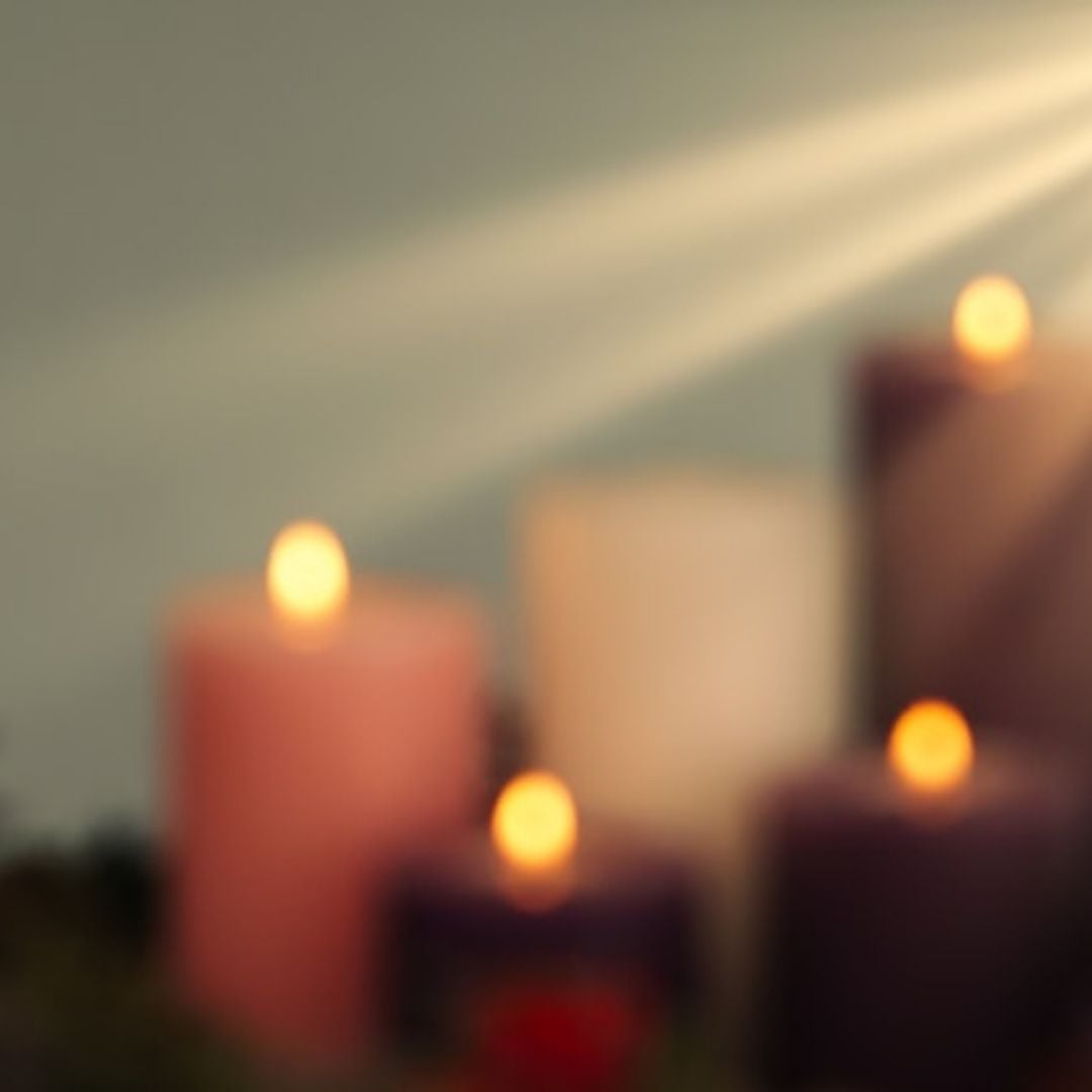 blurred advent candles with a ray of light shining on them