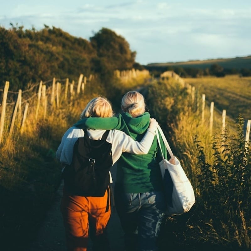 two friends walking arm in arm