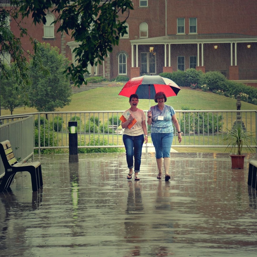 two friends sharing an umbrella walking in the rain